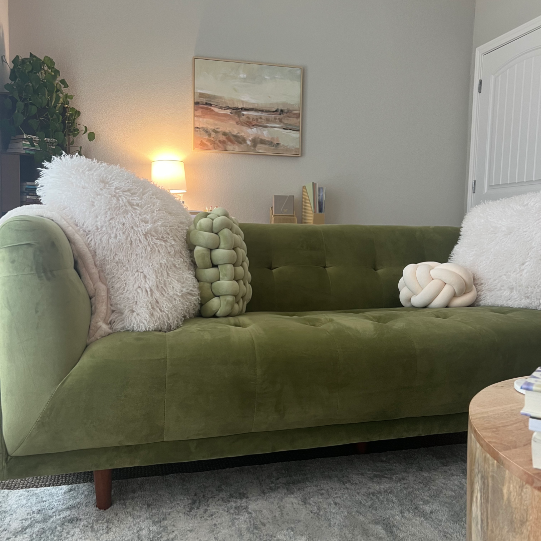 Cozy counseling office with a green velvet sofa, soft textured pillows, warm ambient lighting, and calming wall art.